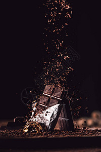 黑色的木桌两块巧克力条上落下的凝胶巧克力图片