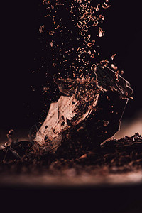 黑色背景的巧克力碎片上掉落的深色巧克力贴近画面背景图片