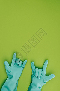 以绿色隔绝的橡胶保护手套中显示岩石标志的妇女作图片
