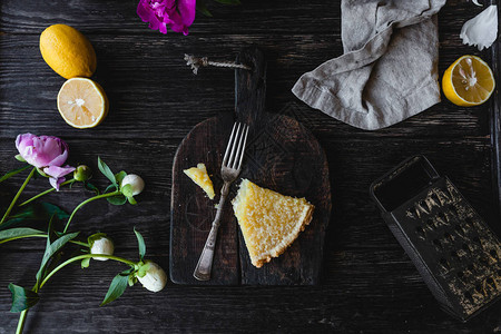 木桌上一块美味的柠檬派和鲜花的顶部视图图片