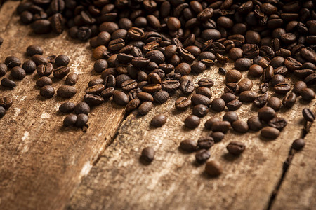 木桌背景上溢出新鲜咖啡豆的近图片
