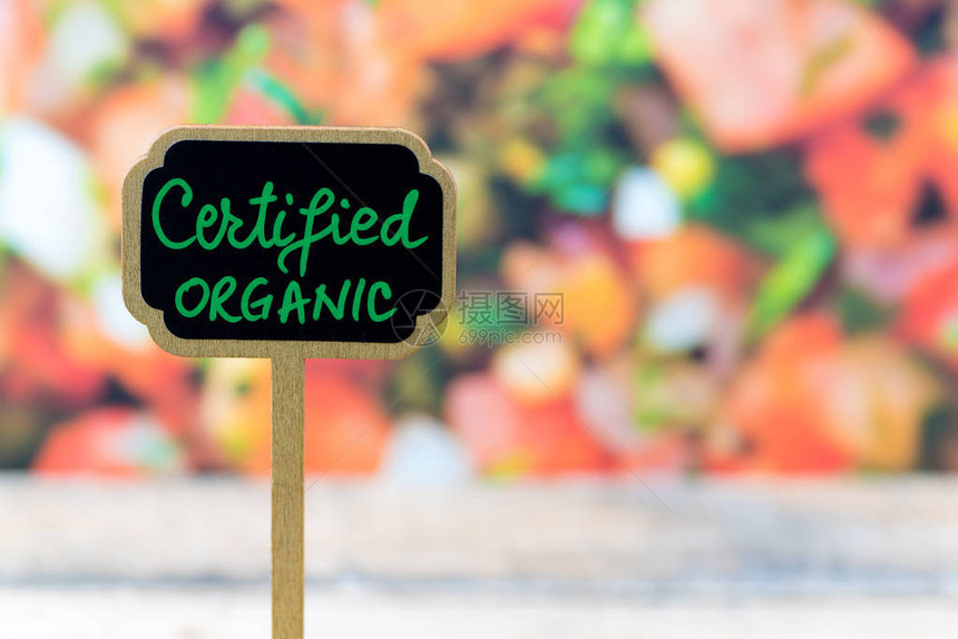 在蔬菜沙拉背景和配有CERTIFIEDOTOC信息表格上贴木制小型黑板标签图片