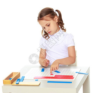 蒙台梭利幼儿园的一个小女孩坐在一张桌子旁学习蒙台梭利的东西图片