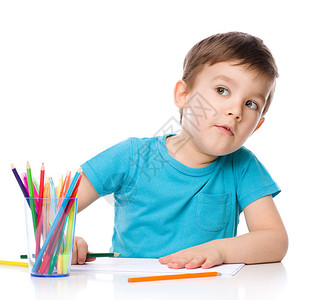 可爱的男孩正在用彩色铅笔画被白色隔开图片