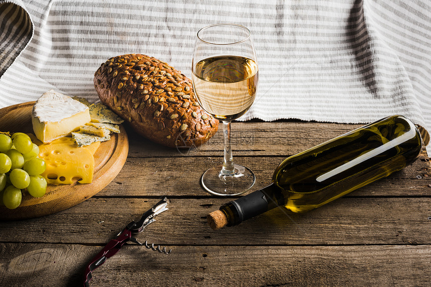 白葡萄酒葡萄酒杯不同奶酪和面包图片