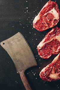 厨房表面生肉牛排和切肉刀的顶部视图图片
