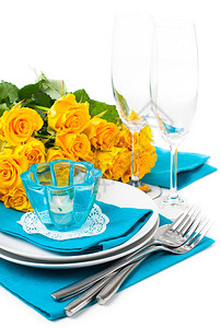配有黄色玫瑰眼镜蜡烛餐巾和蓝色和黄色图片