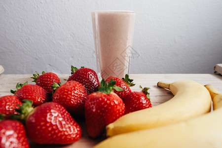 草莓香蕉冰沙新鲜混合在木桌上图片