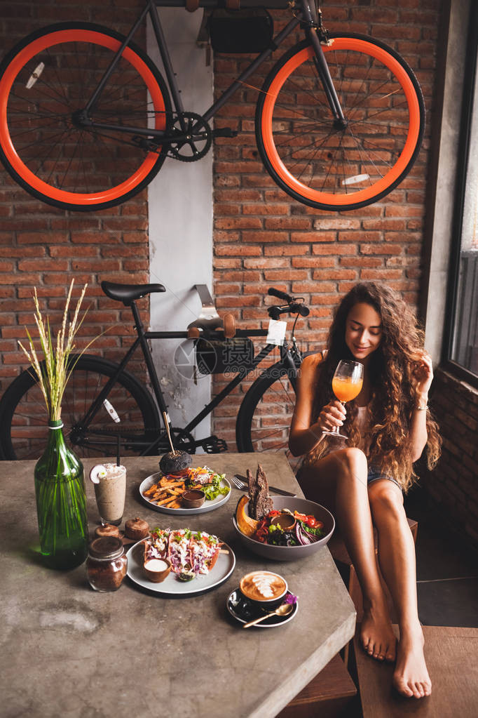 妇女享受新鲜有机素食品和在流行式咖啡厅中一杯图片