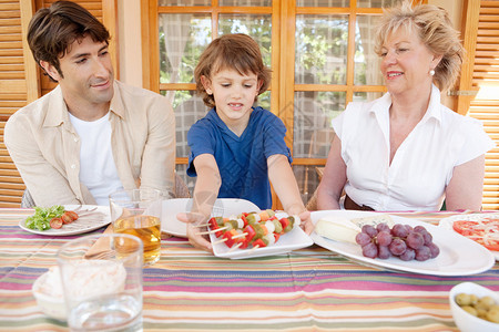 一个家庭的三个亲戚一起坐在家里的户外餐桌旁图片