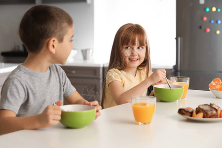 有趣的小孩在家吃早餐和喝柑橘汁图片