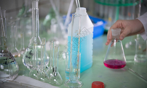 化学实验室触摸瓶子的手把桌子拉上来高清图片