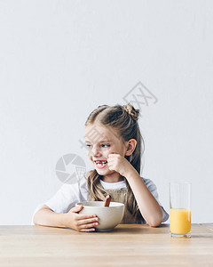快乐的小女学生带着早餐碗和橙汁图片