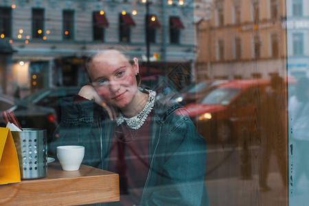 端着一杯咖啡坐在咖啡馆里的女孩图片