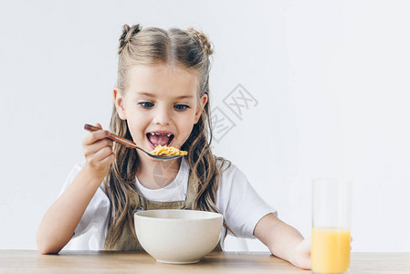 兴奋的小女学生吃健康的早餐孤立图片