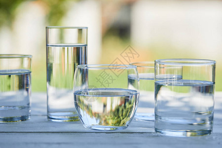 在木制桌的阳光下用透明的玻璃杯图片