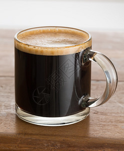 木桌上小玻璃杯中的黑色特快咖啡背景图片