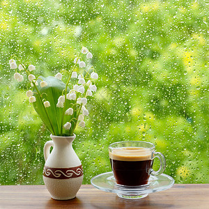 一束花瓶里的山谷百合花和一杯咖啡放在木制桌子上图片