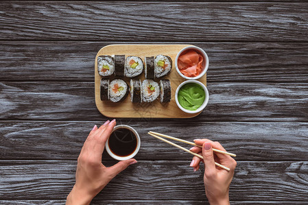 在吃寿司时拿着筷子和碗加酱图片