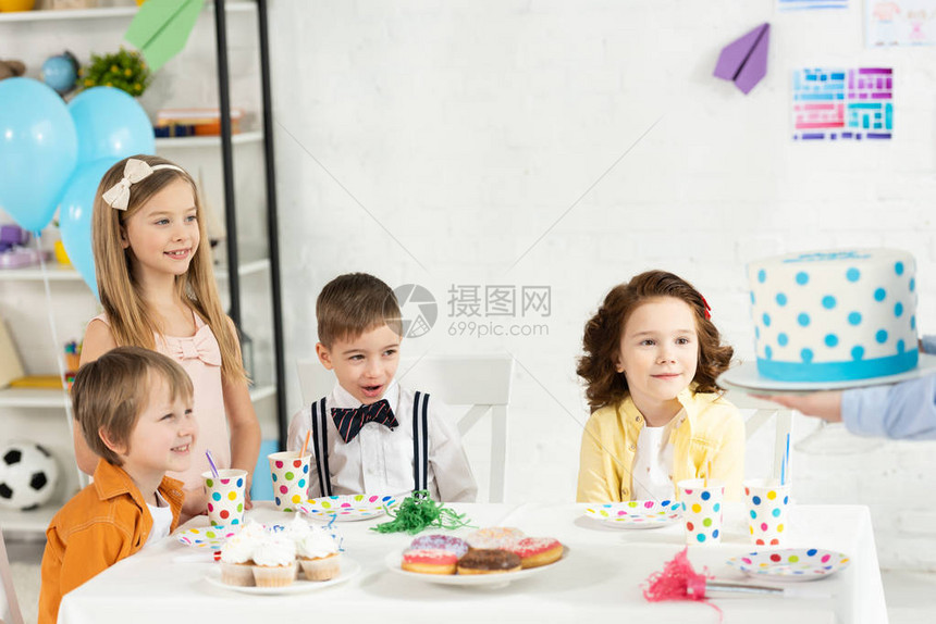 可爱的小孩坐在桌边在生日图片