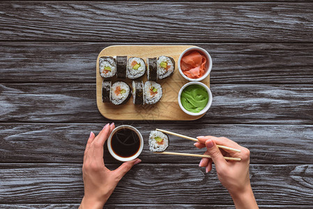 拿着筷子吃美味寿司卷的人裁剪镜头图片