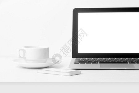 用空白屏幕移动电话和咖啡杯在白背景工作桌上的笔记本电脑近图片