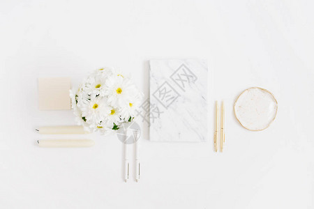 平躺式家庭办公桌女工作区与洋甘菊花束和白色背景上的大理石日记顶图片