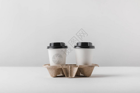 纸杯中的两杯咖啡放在桌面上的纸板托盘中图片