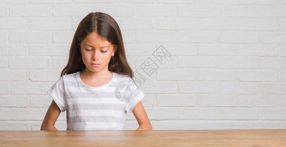 坐在家里桌子上坐着的年幼的西班牙小孩情绪低落图片