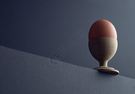 桌边黑背景的鸡蛋杯中的棕蛋图片