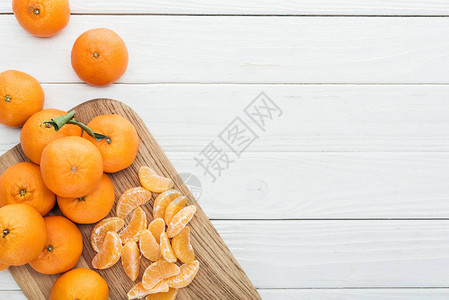 木切面板上剥皮的橘子切片和整图片
