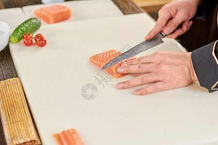 厨师切菜新鲜生鲑鱼片用刀砍手切割白板上的鲑鱼在专业厨图片