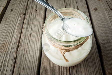在罐子里自制有机酸奶汤匙放在生锈的木制桌子图片