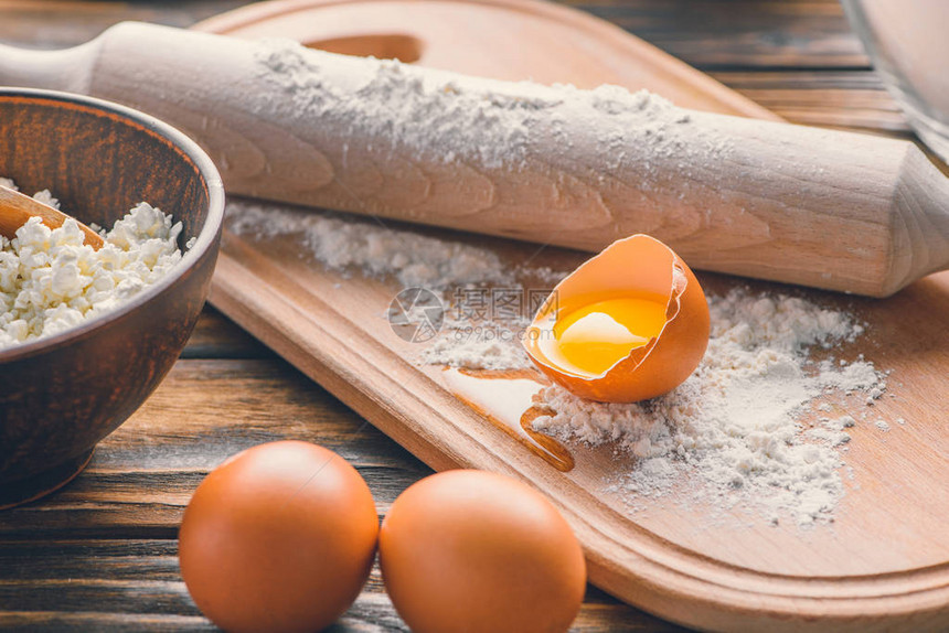 木桌上生鸡蛋带擀面杖的面粉和干酪的特写镜头图片
