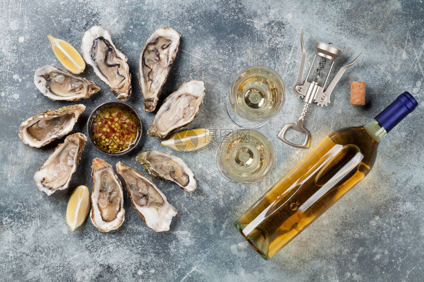 石桌上的新鲜牡蛎和白葡萄酒顶视图图片