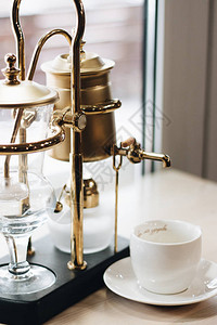 一杯美味的咖啡和复古风格的咖啡机特写图片