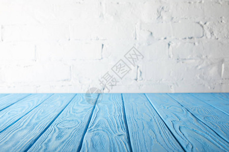 浅蓝色木桌面和带砖的白墙背景图片