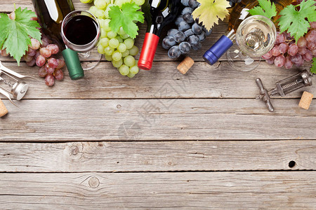 木制桌上的酒瓶和葡萄带有空图片