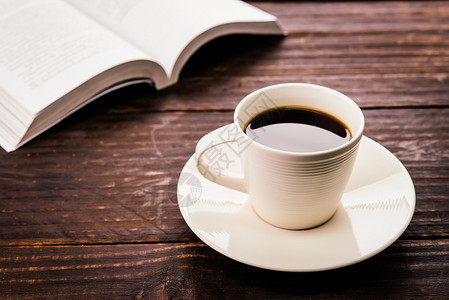 白色咖啡杯和木桌背景上的打开书图片
