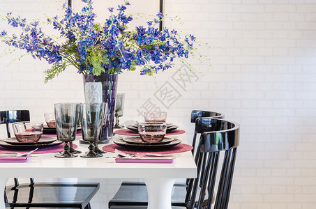 白色餐桌上的花和餐厅的黑色椅子图片