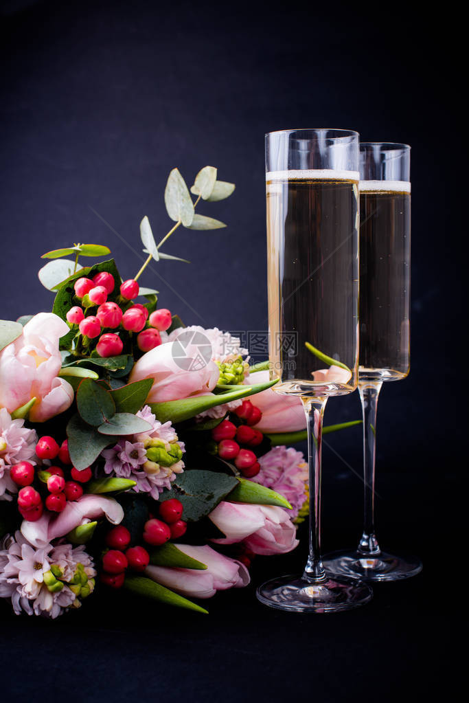 两杯香槟和一束黑底的粉红花图片