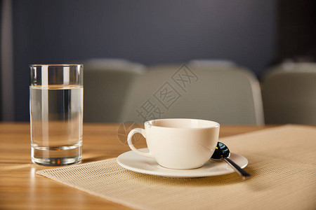 咖啡杯在咖啡厅里有水的玻璃附近的咖啡图片