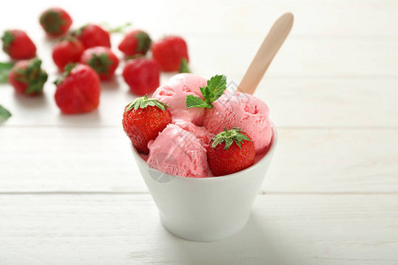 白色木质背景中带美味草莓冰淇淋的碗图片