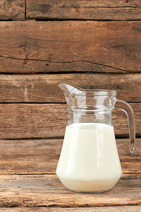 玻璃壶中的有机牛奶天然牛奶在质朴的木板上的玻璃投手牛图片