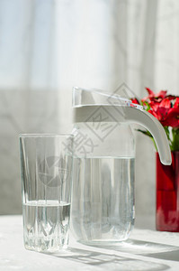 白桌上的白水壶和一杯清水图片