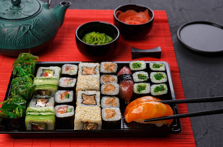 吃鲑鱼寿司日本食品餐厅寿司马基和卷盘或子架放图片