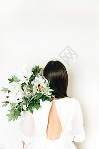 白色背景上拿着白牡丹花束的女人图片