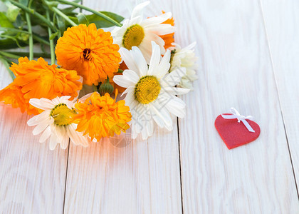 浅色木桌上的雏菊和金盏花束背景图片