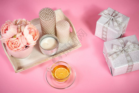 浅粉红背景的木托盘茶叶和礼品上图片