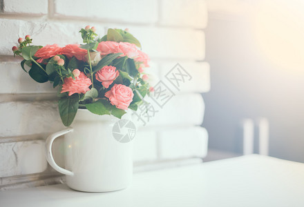 白砖墙背景的陈年咖啡壶中的粉红玫瑰花盆背景图片